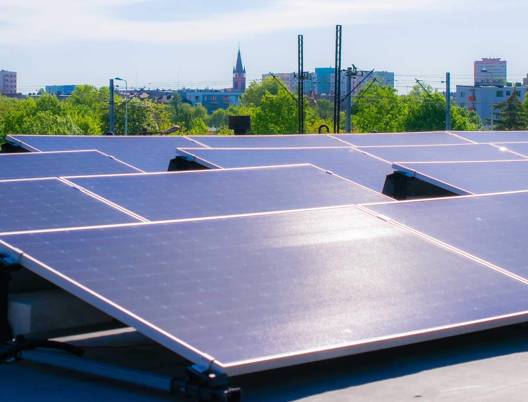 Photovoltaikmodule auf einem Flachdach in einer Großstadt. Sonne scheint auf die Module.