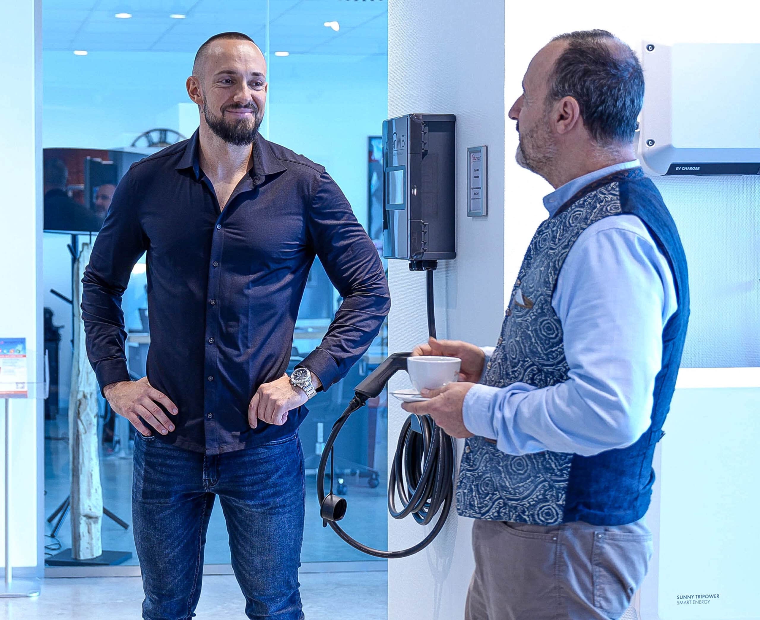 Zwei lachende Männer bei Gespräch in Photovoltaik Ausstellung von naturwaerme.