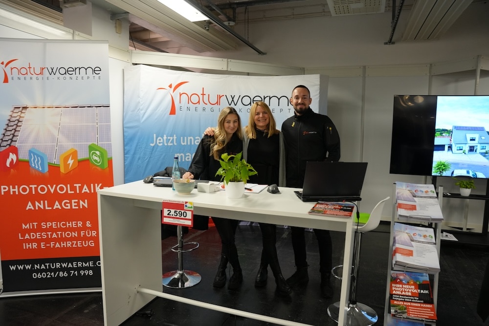 Drei lächelnde Berater von naturwaerme auf der Baumesse Offenbach