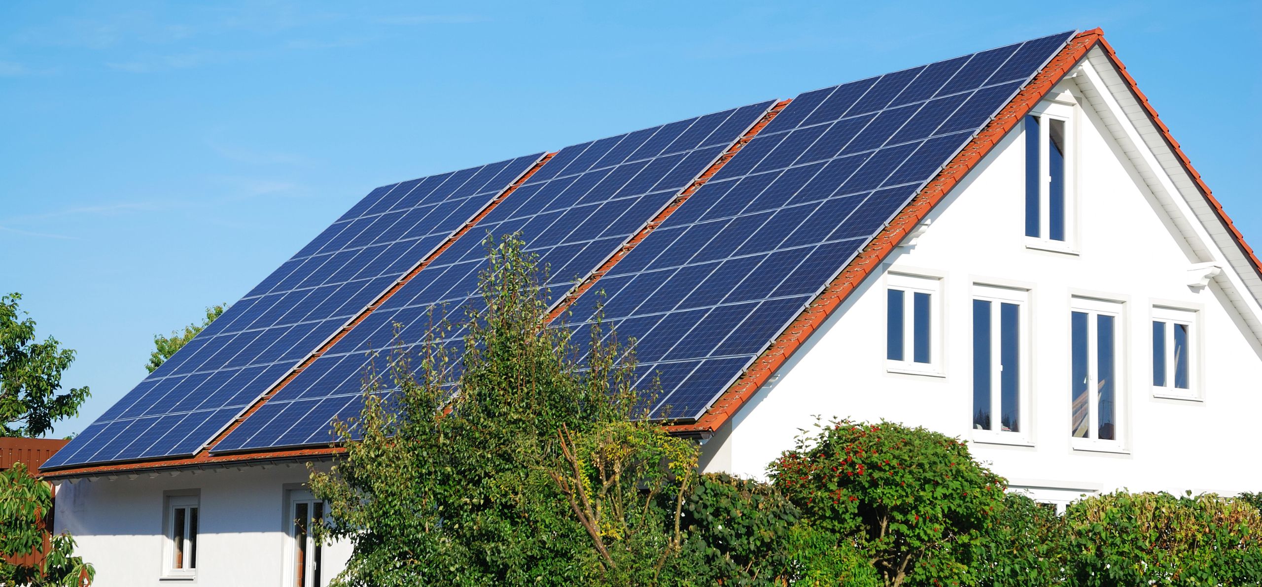 Haus mit roten Dachziegeln und großer Photovoltaikanlage.