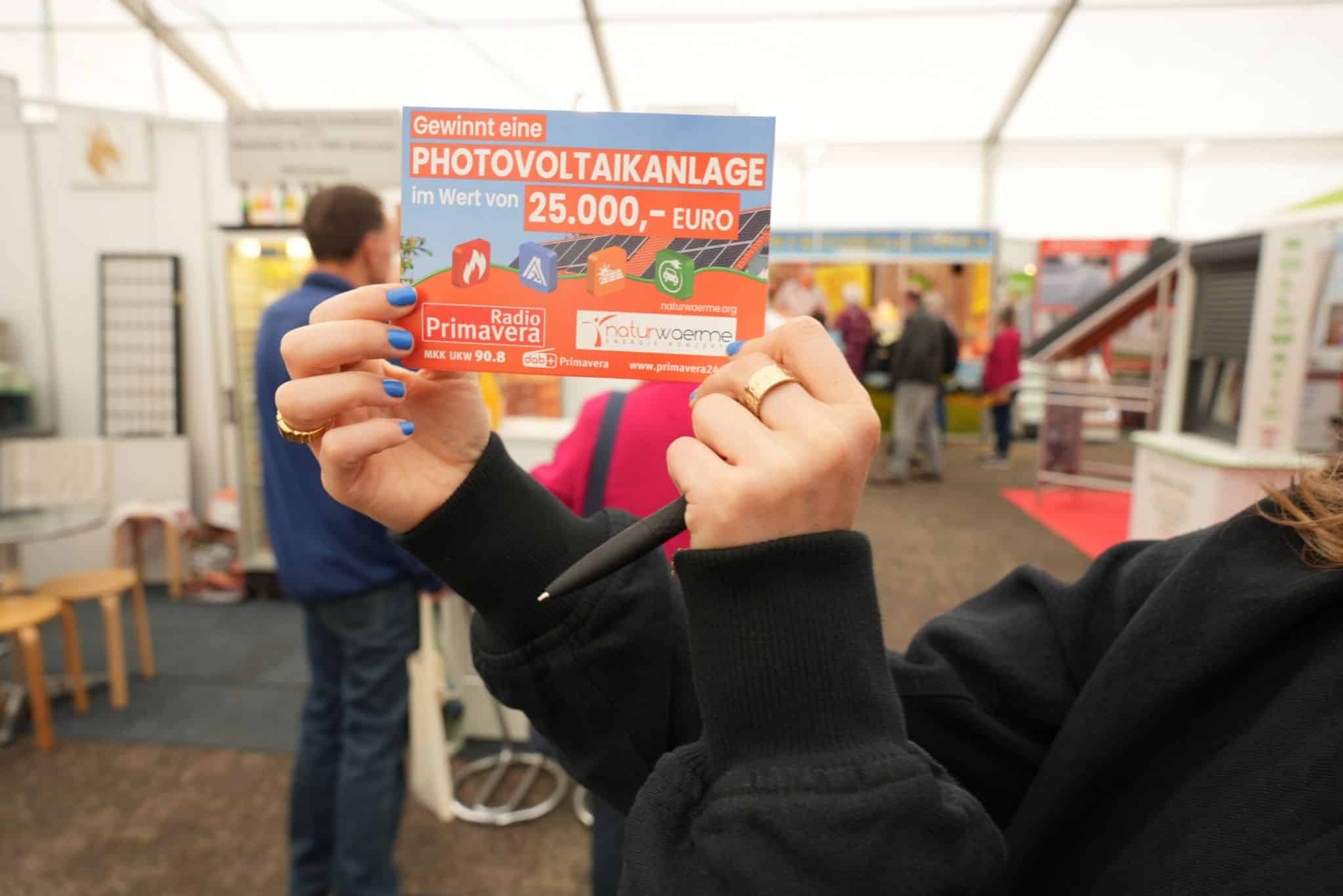 Person hält Gewinnkärtchen mit beiden Händen in die Kamera