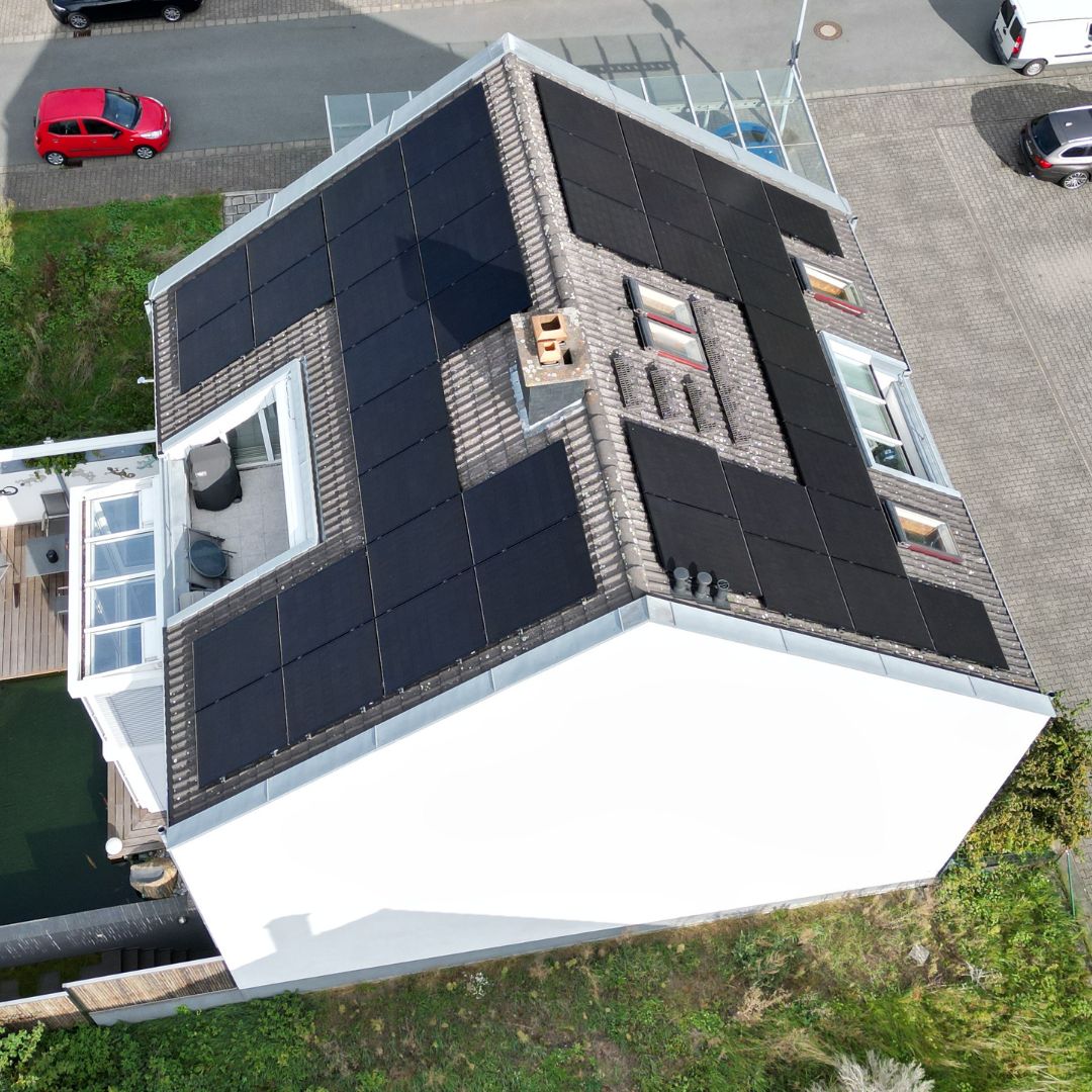 Weißes Reihenhaus mit Photovoltaikanlage auf dem Dach.