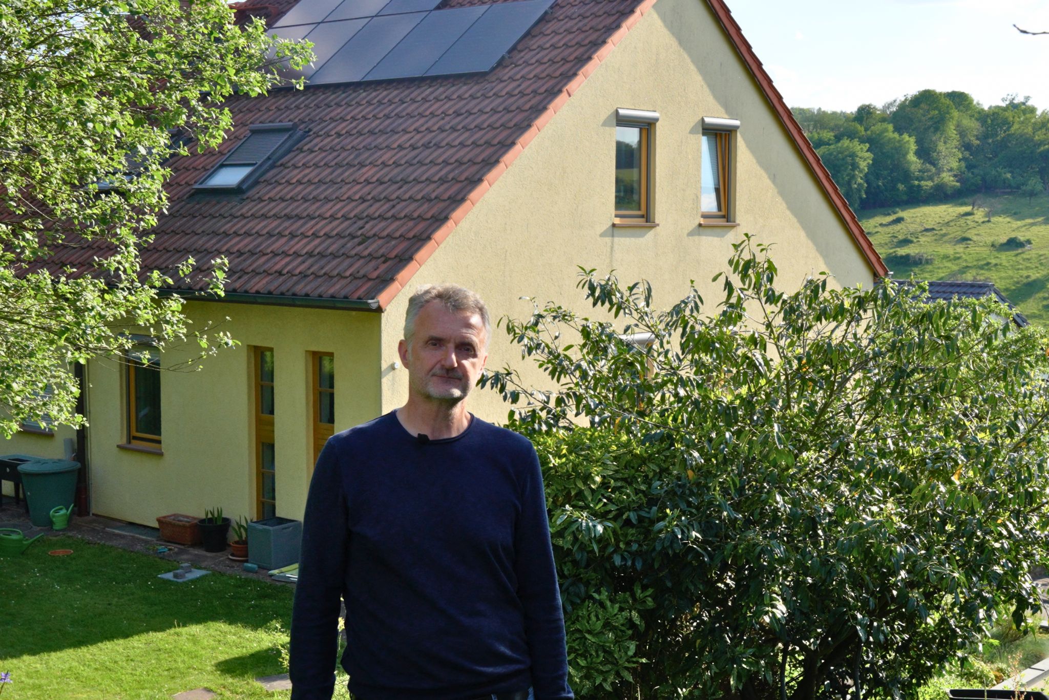 Michael steht vor seinem Haus mit Photovoltaikanlage