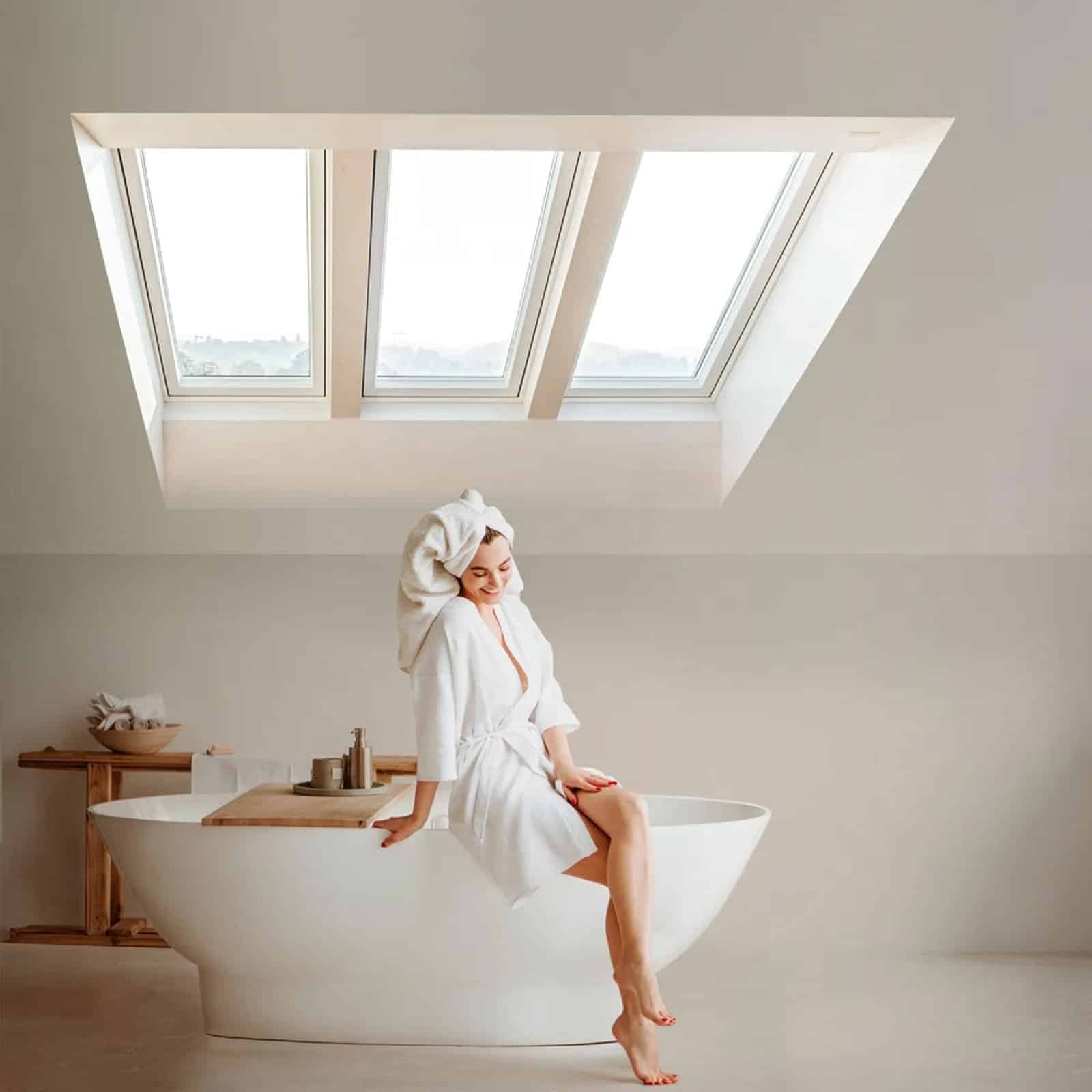 Frau sitzt im Badezimmer im Dachgeschoss auf der Badewanne
